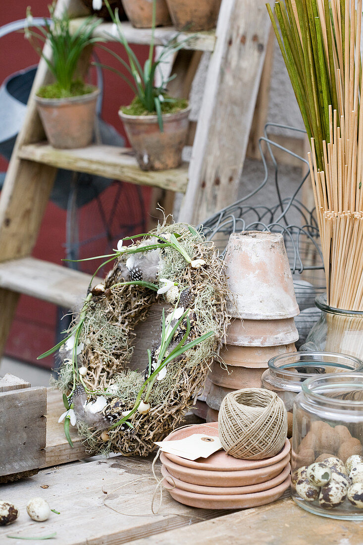 Rustic Easter wreath decorated with lichen and feathers next to craft materials