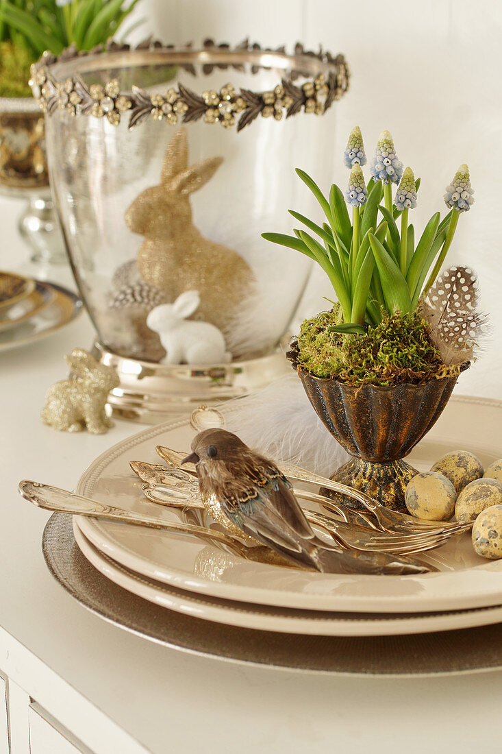 Easter decoration with grape hyacinths in silver cups, Easter eggs, birds, silver cutlery, and Easter bunnies