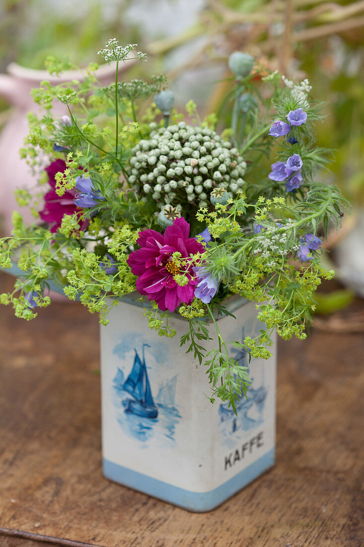 Bouquet of cosmea, lady's mantel, viper's bugloss, allium and poppy seed heads in tin