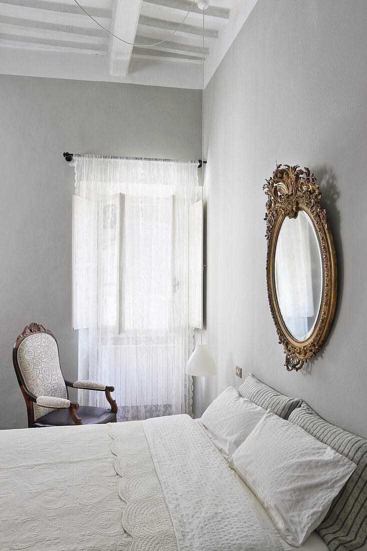 Goldrahmenspiegel über Doppelbett im Schlafzimmer mit hellgrauen Wänden