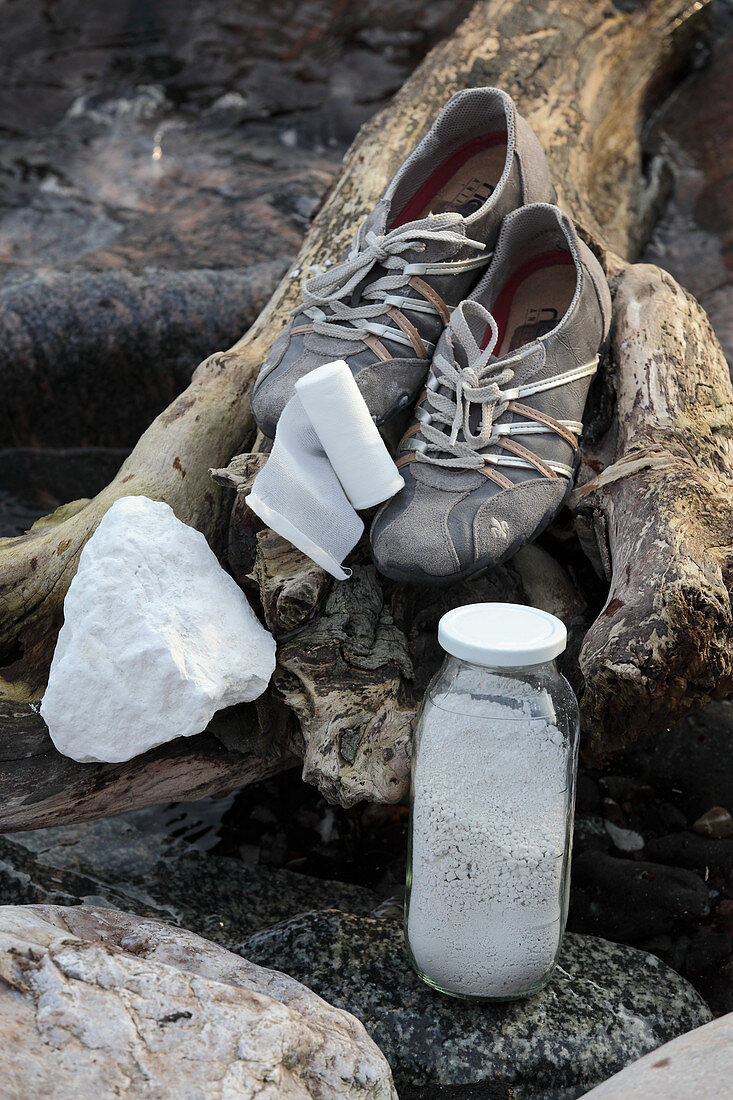 Training shoes, talcum powder and gauze bandage on piece of driftwood