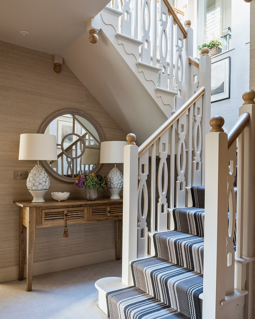 Console table below staircase in classic, beige foyer