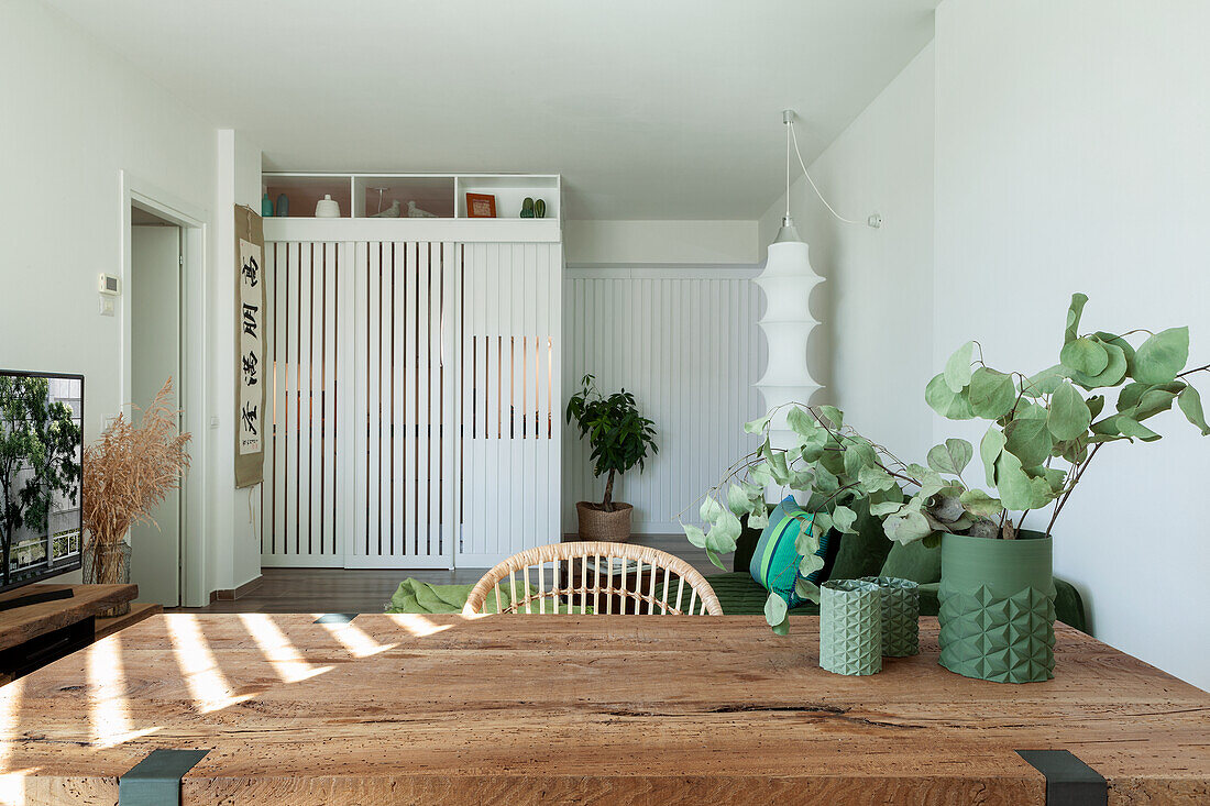 Vase mit Eukalyptuszweigen auf Esstisch mit Holzplatte