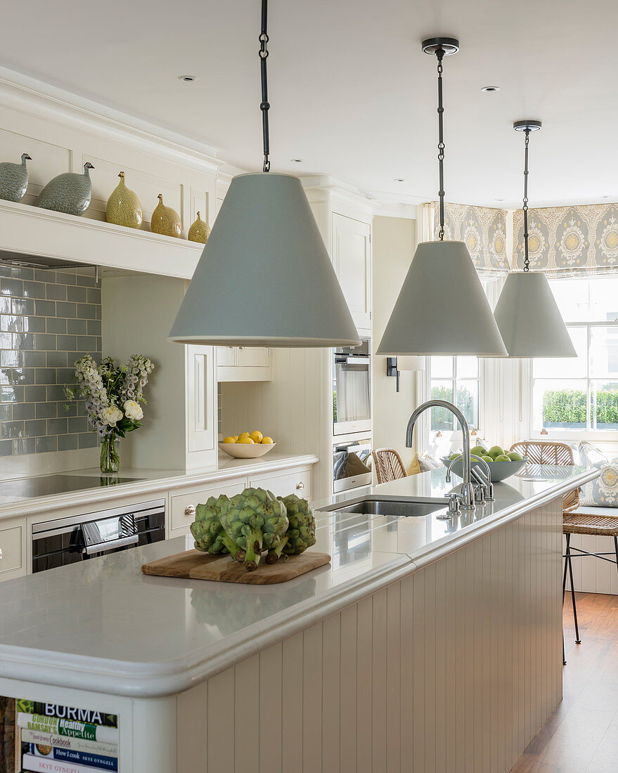 Pale blue lamps above island counter in classic kitchen-dining room