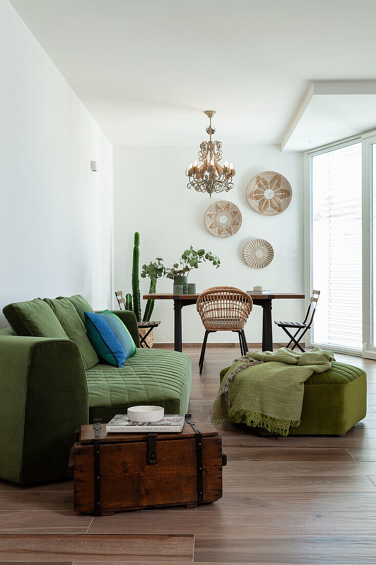 Alte Holztruhe als Beistelltisch und grüne Polstermöbel in offenem Wohnraum