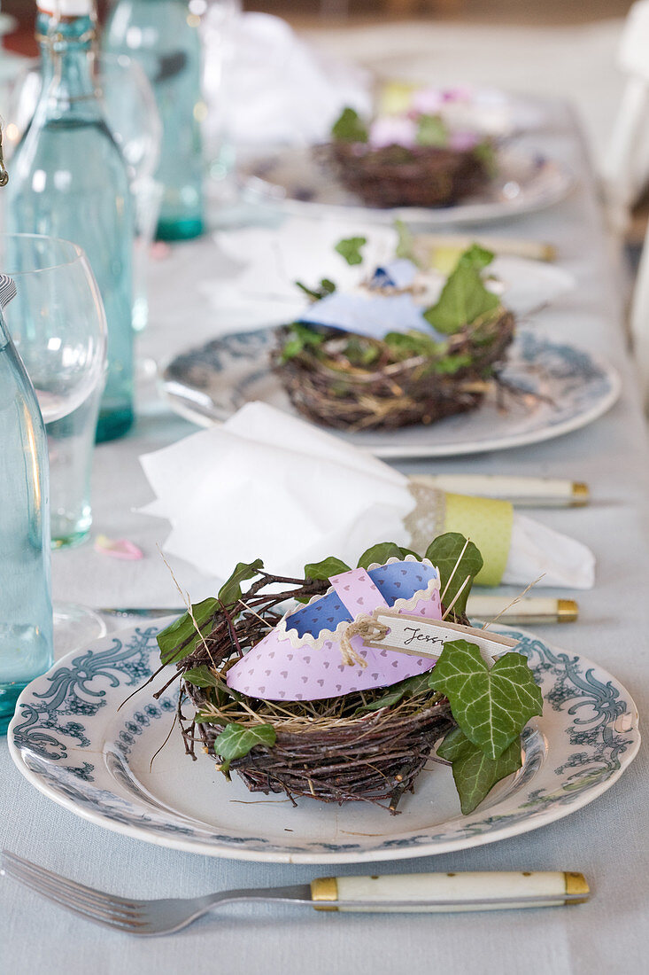 Homemade paper baby shoes in nests as place cards