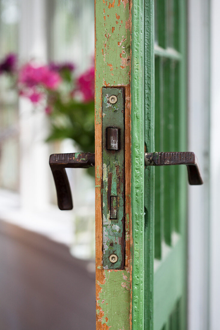 Alter Türbeschlag einer grünen Tür mit Patina