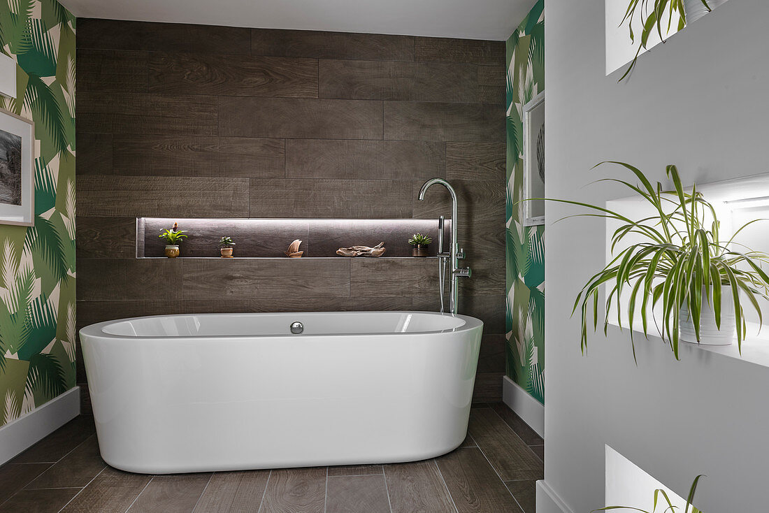 Ovale Badewanne im modernen Bad mit Pflanzen in Wandnischen
