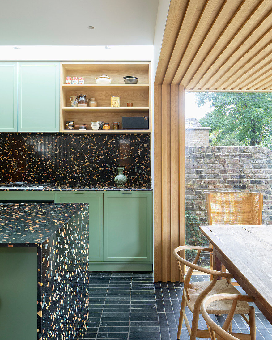 Open-plan kitchen with black terrazzo elements and dining area in extension