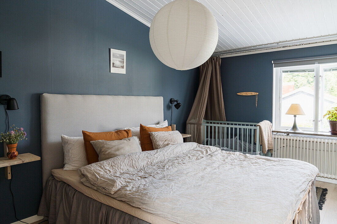 Doppelbett und Babybett im Schlafzimmer mit blauen Wänden