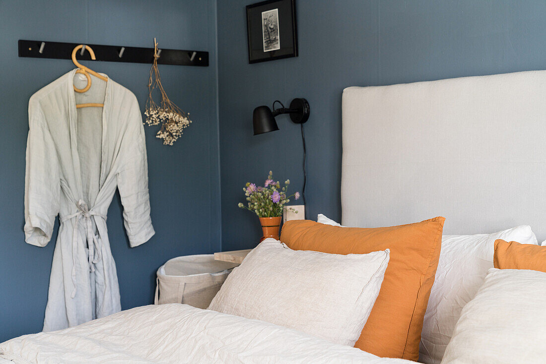 Doppelbett mit hohem Kopfteil im Schlafzimmer mit blauen Wänden