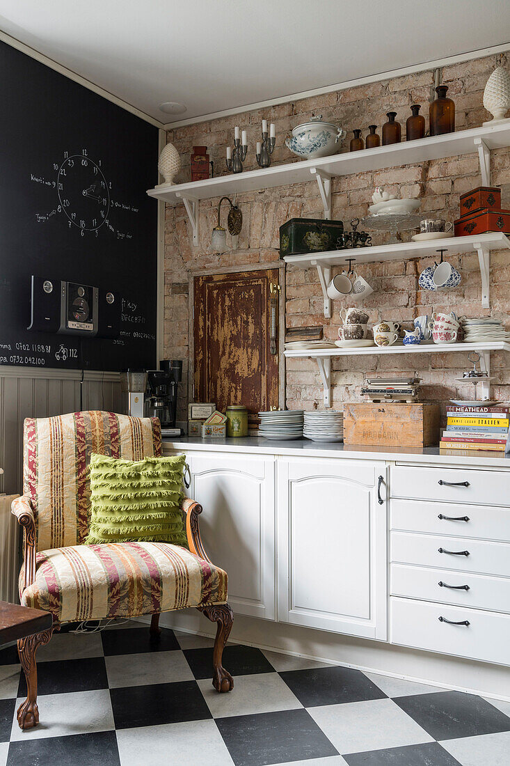 Armchair in corner of kitchen with chequered floor tiles