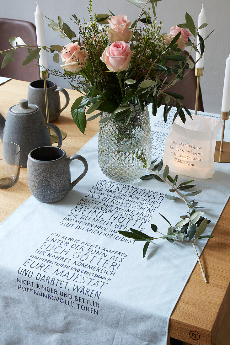 Strauß Rosen auf gedecktem Tisch, Tischläufer mit Schriftmotiv