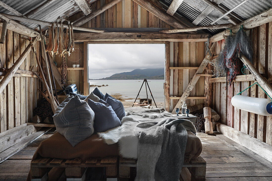 Pillows on bed made from pallets in rustic wooden shed