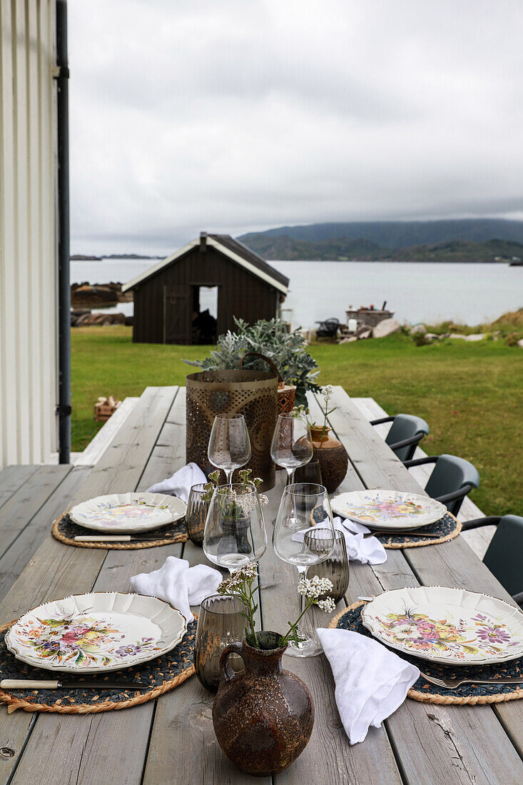 Set wooden table and chairs on terrace with a view of the Lofoten Islands