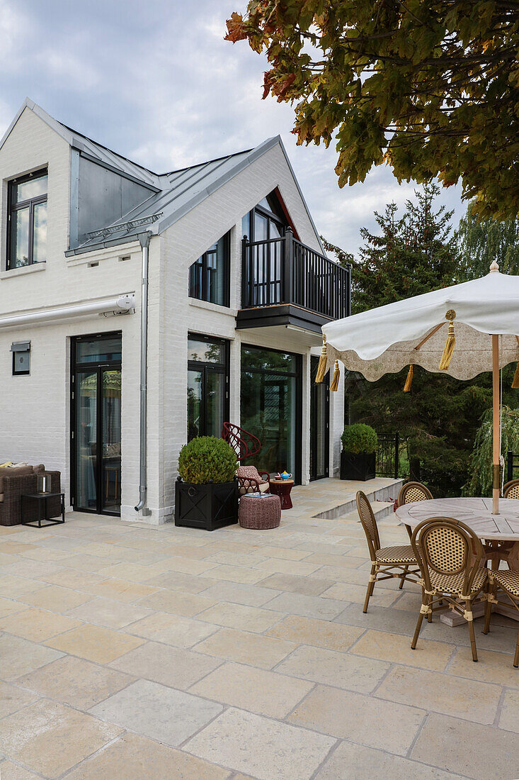 Round table, parasol and chairs on the terrace of a holiday home