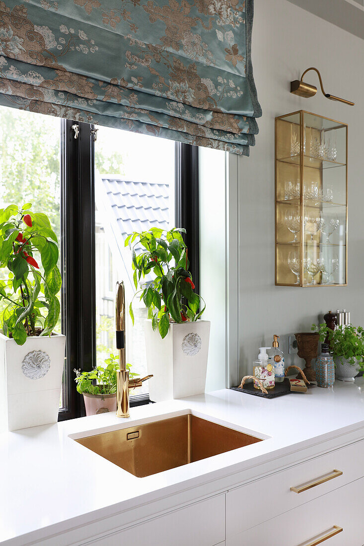 Weiße Küchenzeile mit integriertem Spülbecken vor dem Fenster