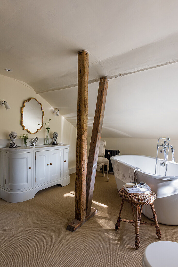 Renoviertes Badezimmer mit freistehender Badewanne, Waschtischmöbel und rustikaler Holzstütze