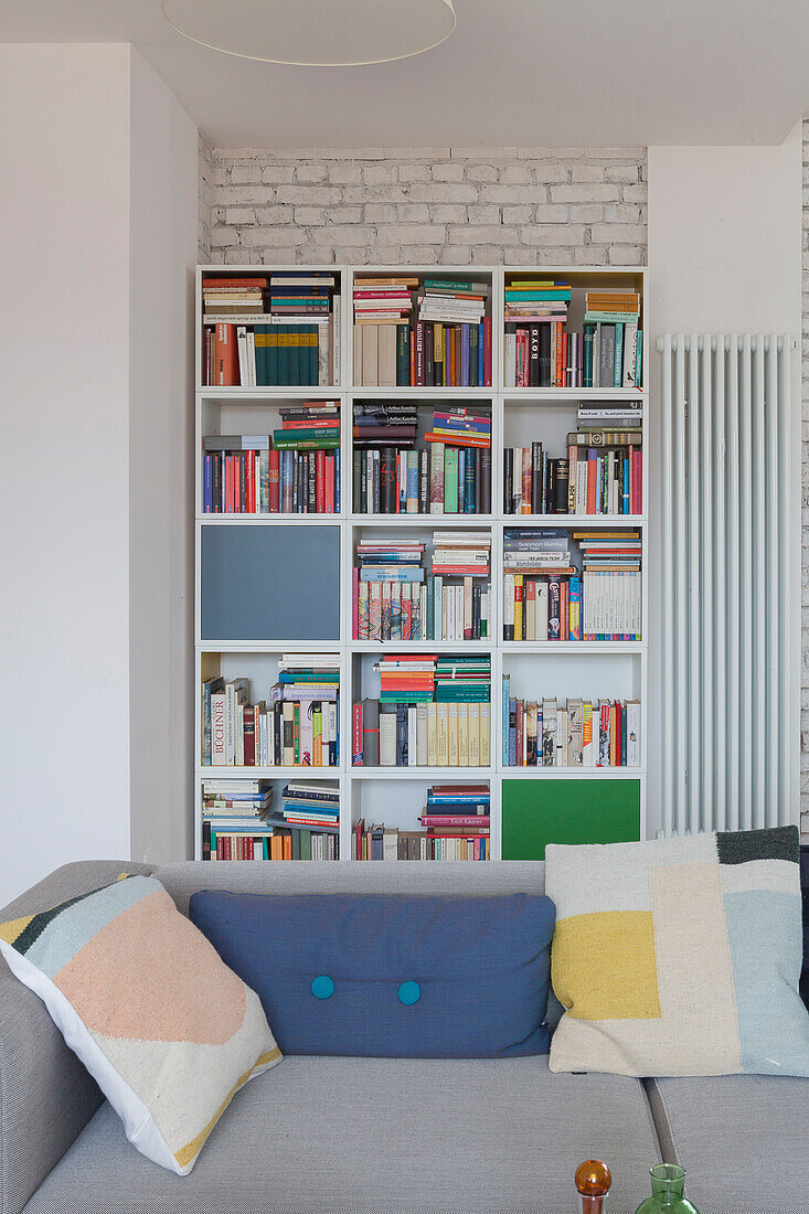Blick über graues Sofa mit Kissen auf Bücherregal