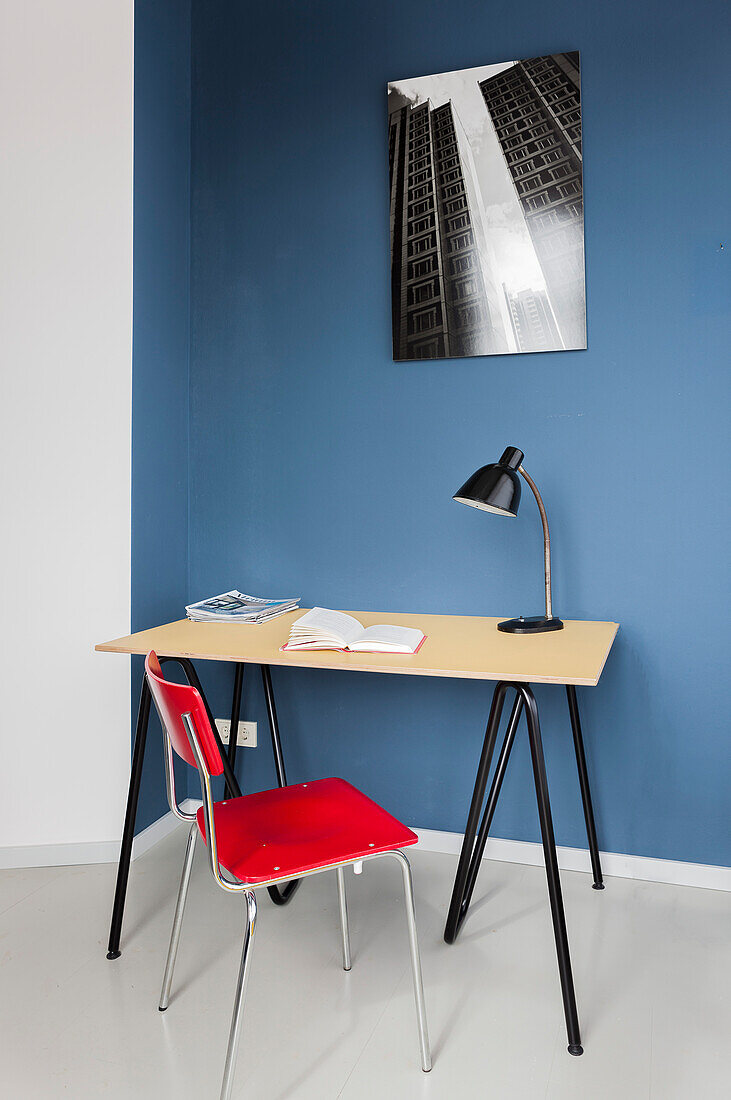Desk and red chair against blue wall in study
