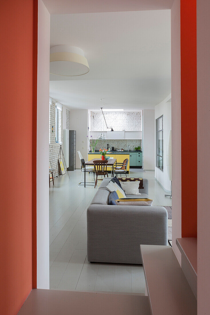 View from staircase with salmon-pink walls into open-plan interior with white-painted floorboards