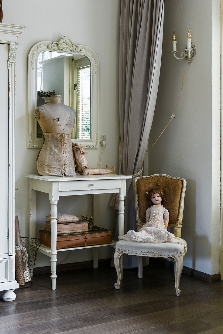 Puppe auf altem Barockstuhl und Modepuppe auf Konsolentisch