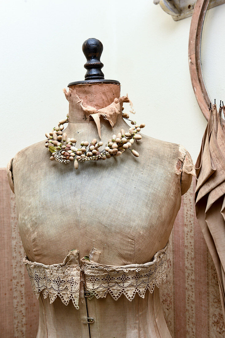 Vintage-style arrangement of old tailor's dummy wearing corset and wreath