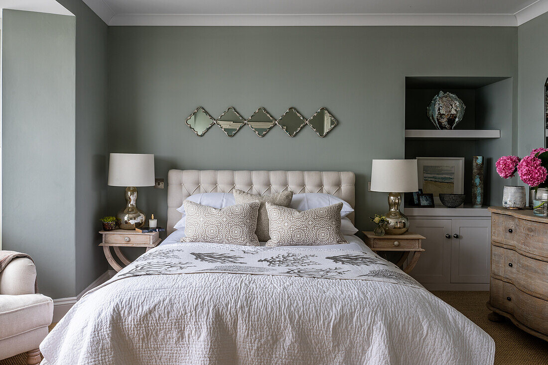 Double bed flanked by two bedside tables with lamps in bedroom with grey walls