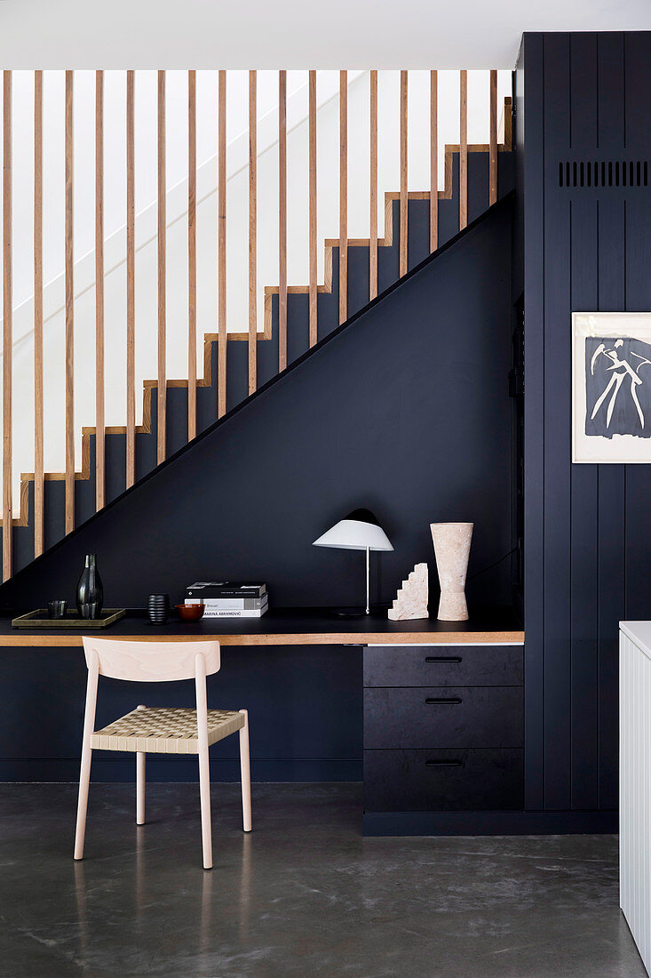 Desk and chair against a black-painted staircase wall