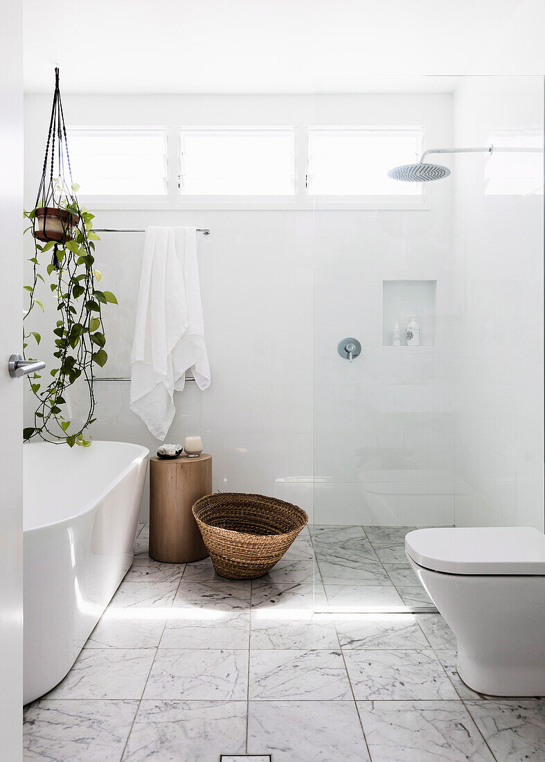 Helles Badezimmer mit freistehender Badewanne und Hängepflanze