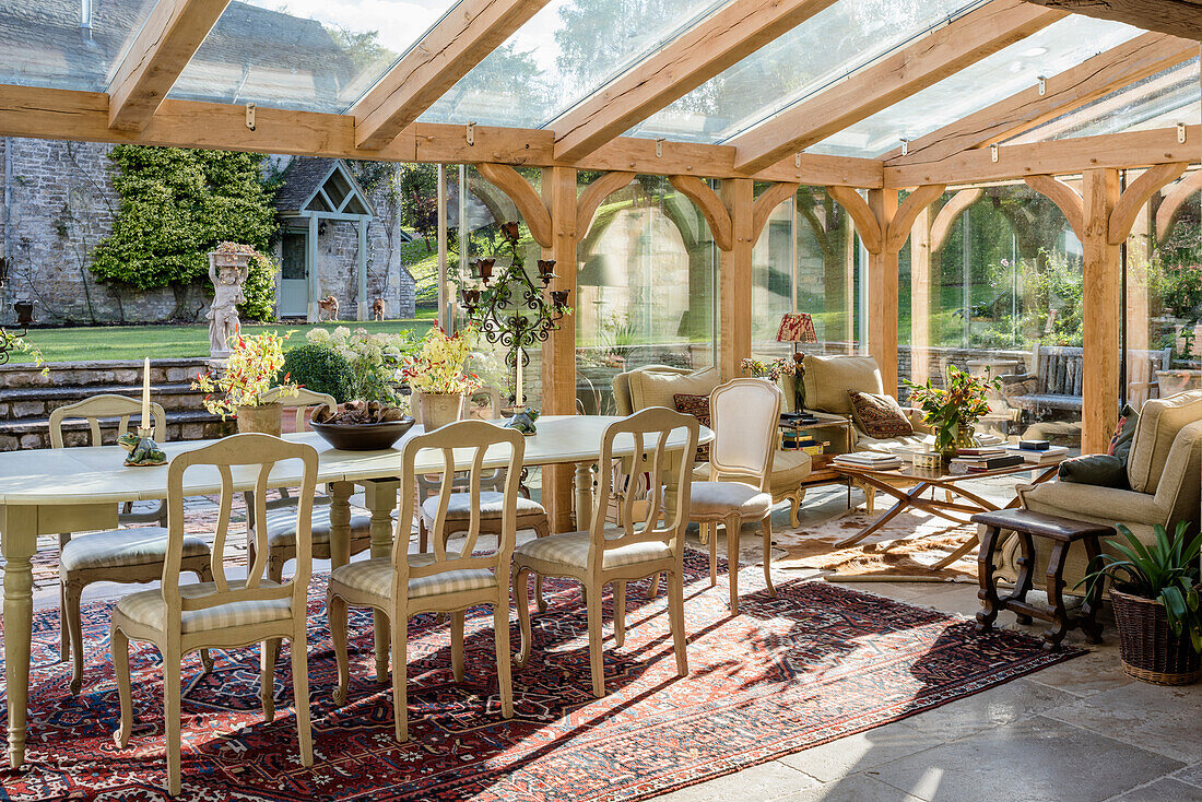 Open plan dining room in glass conservatory extension of 19th century stone farmhouse