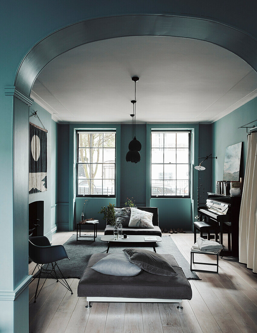 Seating and piano in the living room with petrol-coloured walls