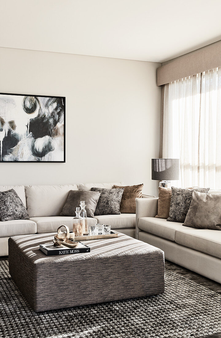 Elegantes Wohnzimmer in Beige und Grau mit gepolstertem Couchtisch