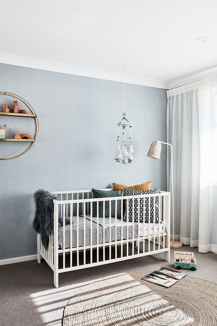 Gitterbett vor hellblauer Wand im minimalistischen Kinderzimmer