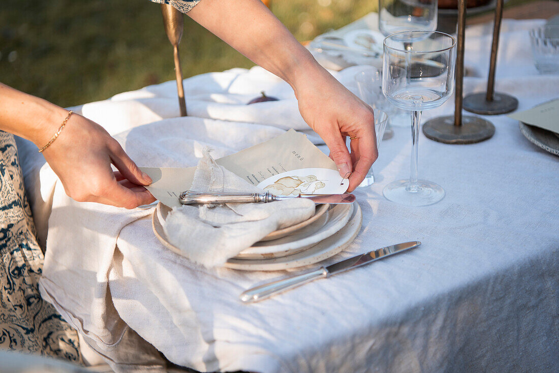 Gedeck mit Leinenserviette auf Gartentisch mit Leinentischdecke