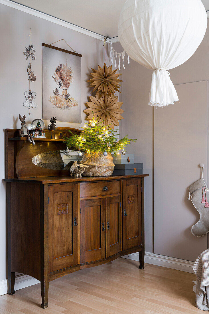 DIY pendant lamp, antique sideboard and brown paper stars in corner of room