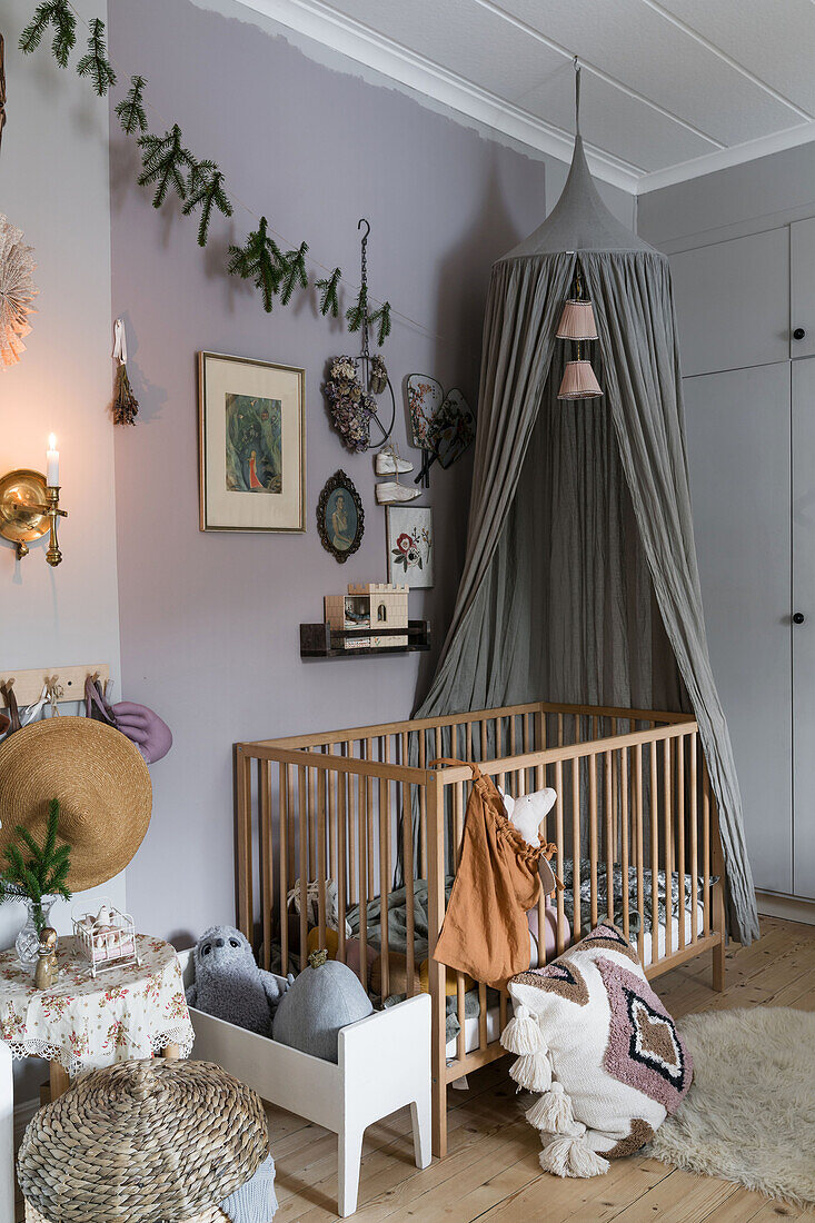 Gitterbett mit Betthimmel im weihnachtlich dekoriertem Kinderzimmer mit grauen Wänden
