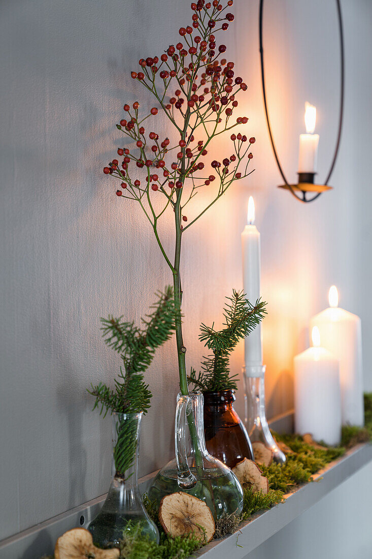Shelf decorated for Christmas with vases, branches and candles