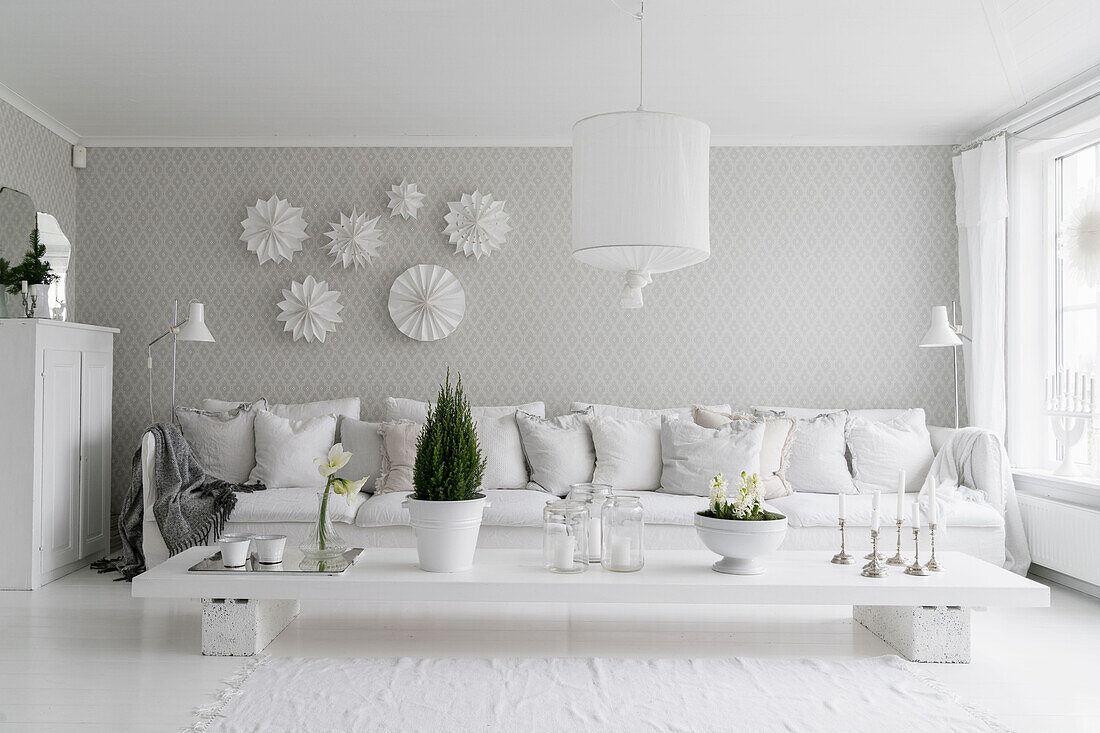 DIY-Couchtisch, Polstersofa mit Kissen und weiße Papiersterne in hellem Wohnzimmer