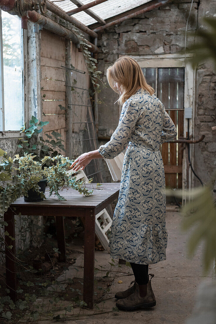 Woman standing next to potting table in greenhouse