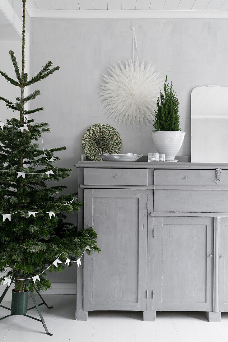 Grauer, halbhoher Schrank und Weihnachtsbaum in hellem Zimmer