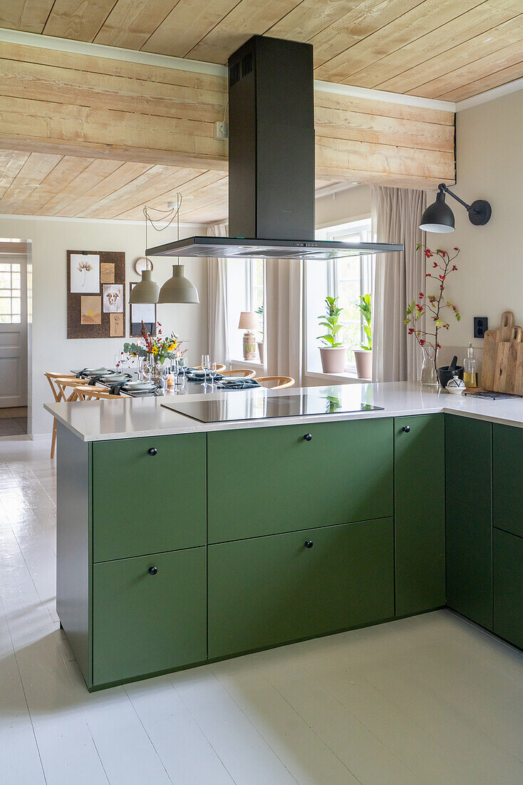 Kochinsel mit grünen Schubladen, darüber Dunstabzugshaub in offener Küche
