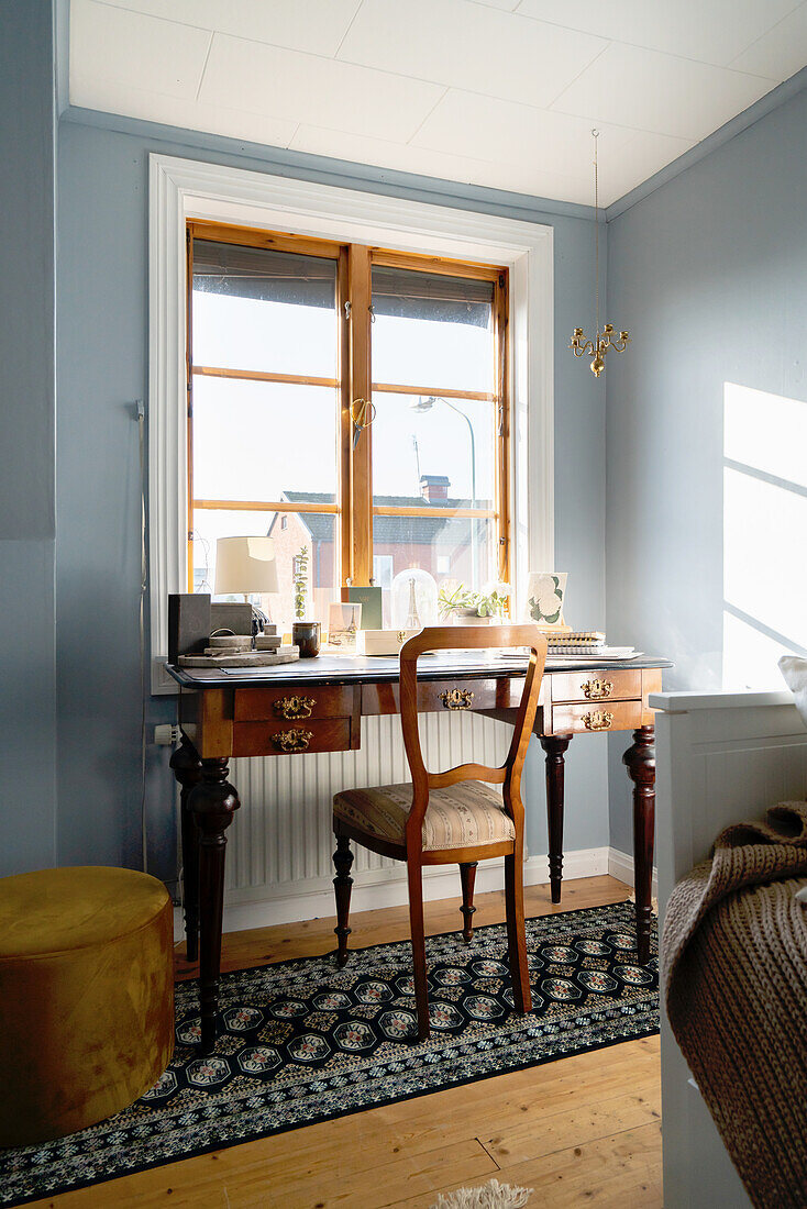 Antique chair and desk by a window on a classic runner