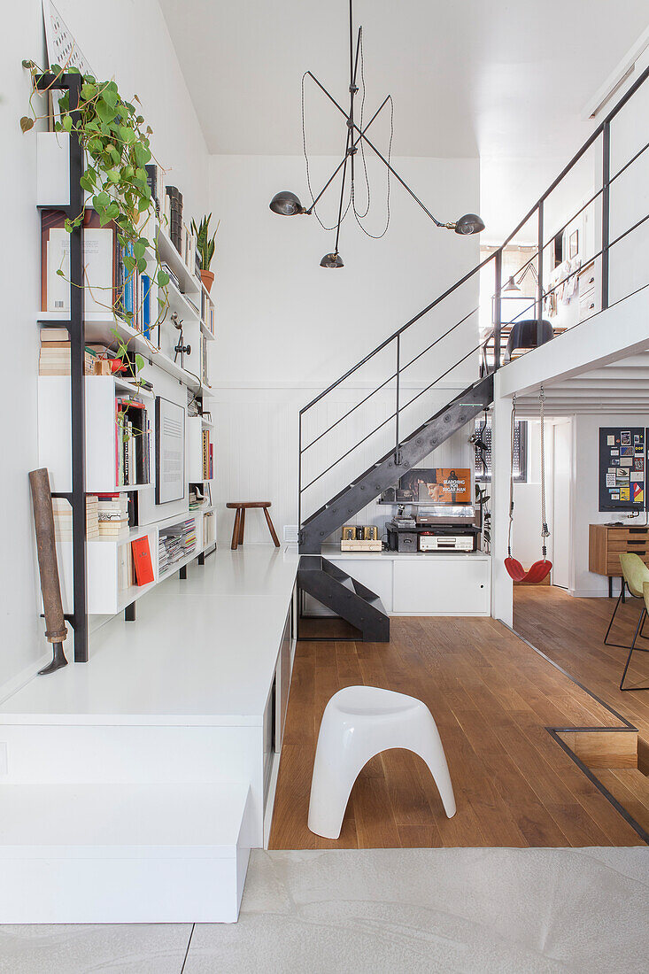 Open shelf on white pedestal and staircase in a loft