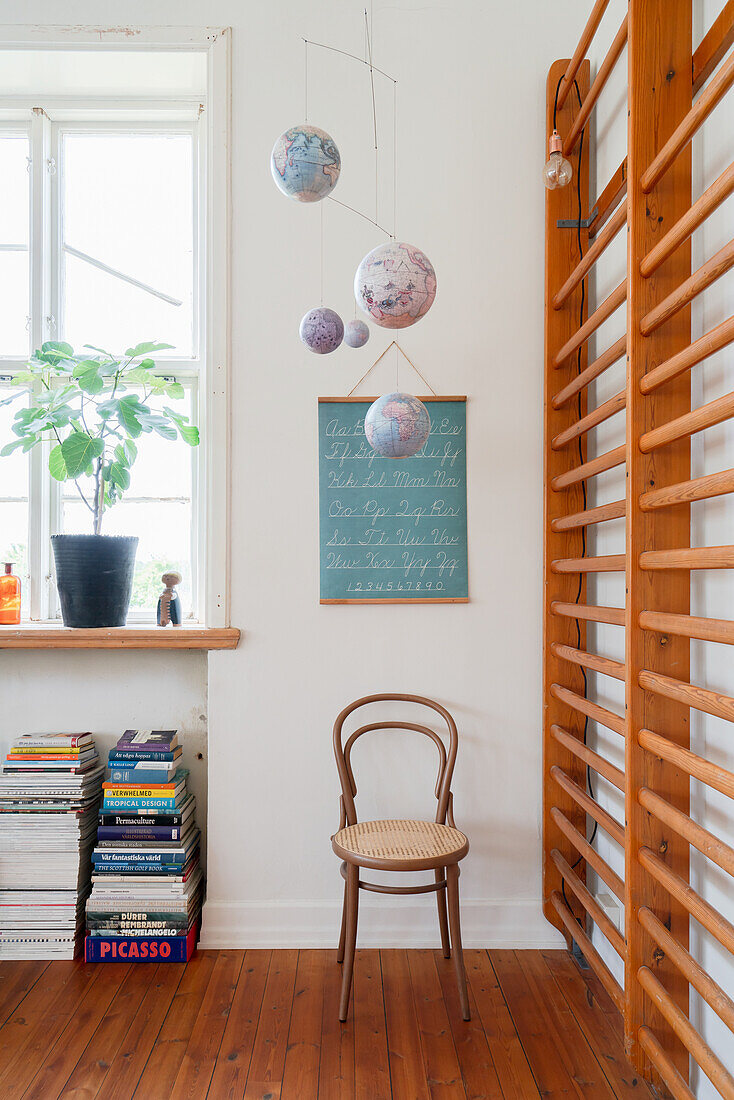 Wall racks, chair, blackboard and hanging globes in the corner of a room