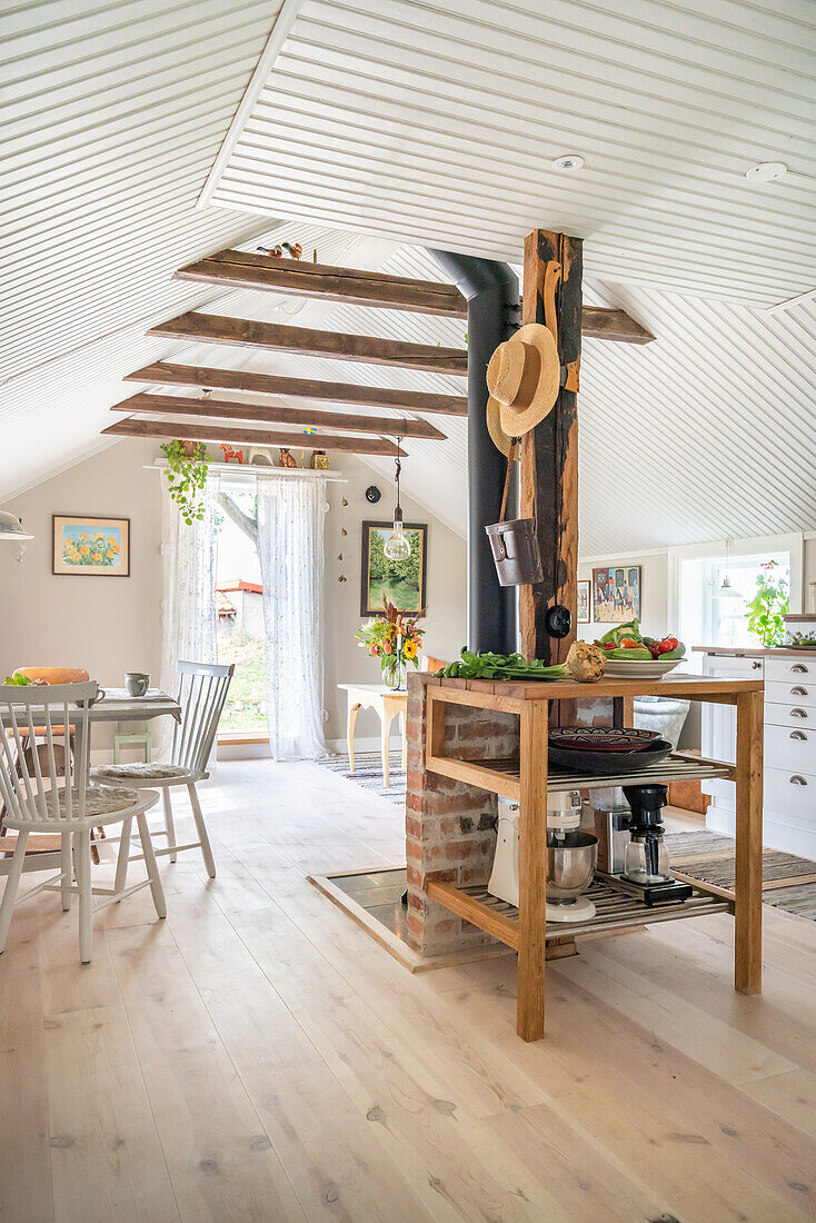 Offener Wohnraum mit Holzdielenboden und weiß gestrichener Holzdecke, Küchenregal im Vordergrund