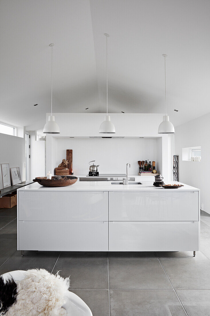 White kitchen island in open living area with concrete tiles