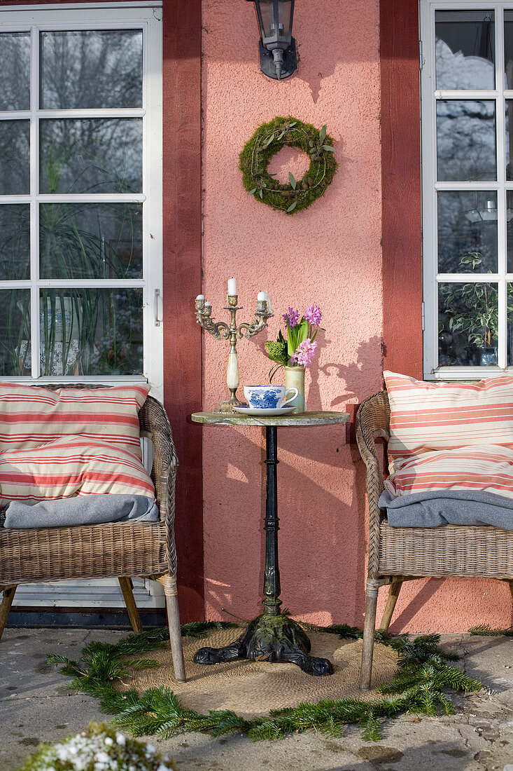 A side table between wicker chairs on a veranda