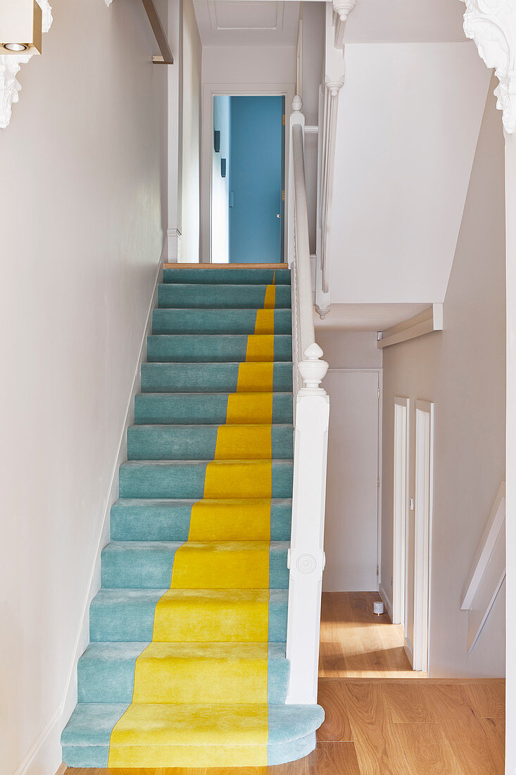 Staircase with blue and yellow carpet in white stairwell