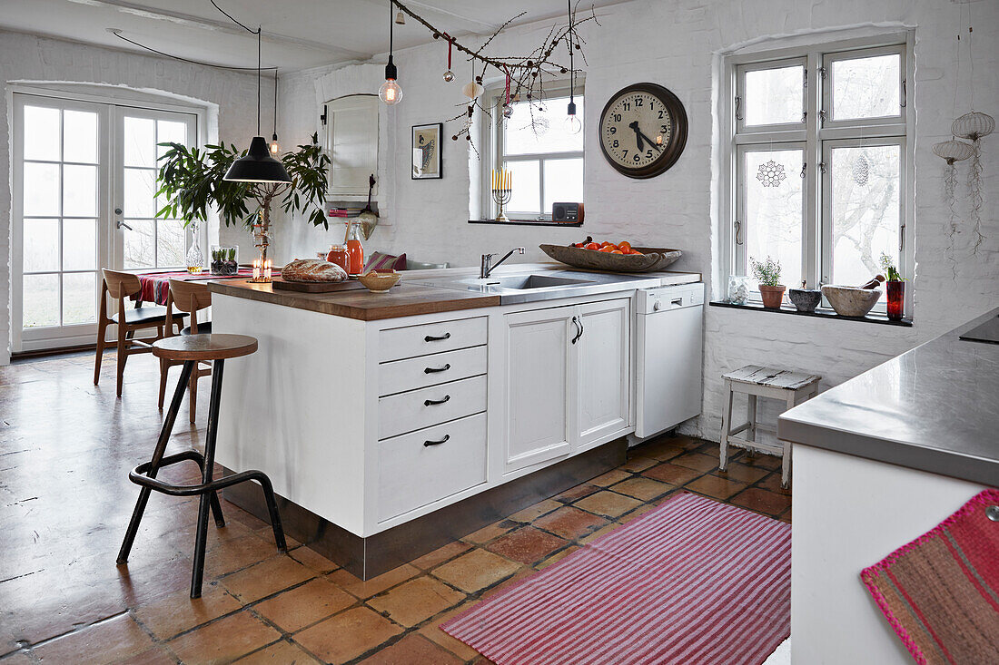 Open, white kitchen with terracotta tiled floor